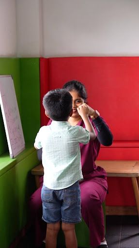Child receiving eye care consultation from a female eye specialist in a colorful clinic room