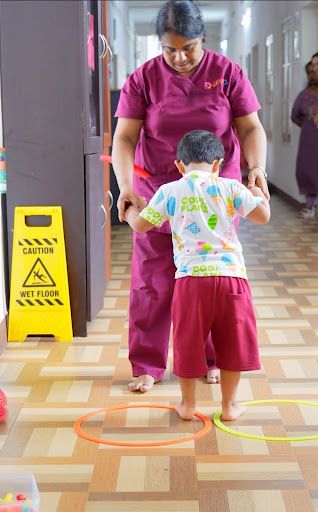 Pediatric therapist and young child smiling and connecting through play in a warm, sensory-friendly therapy room.
