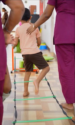 Child undergoing pediatric physical therapy with a therapist during a walking exercise